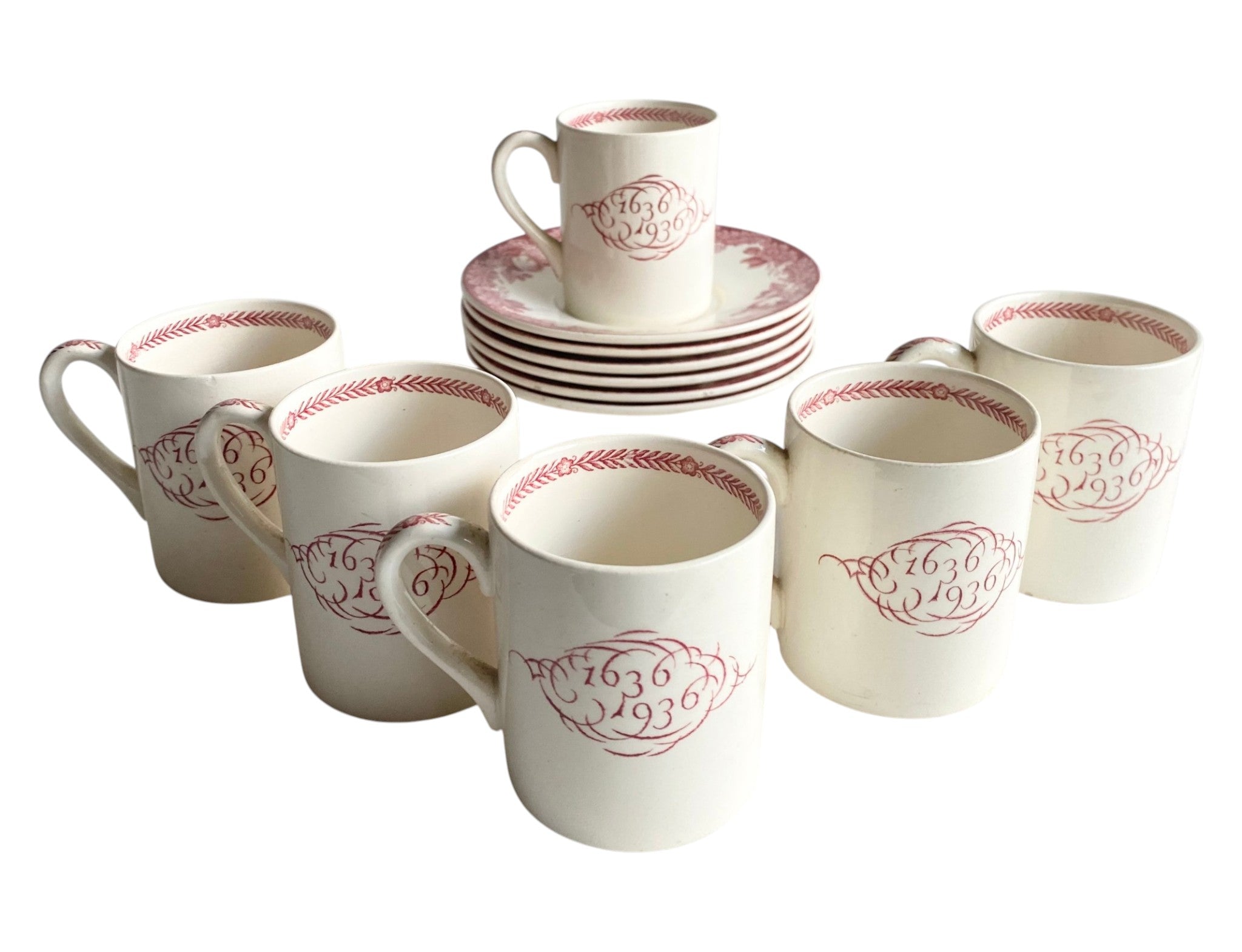 Set of ceramic mugs and plates with red decorative patterns on a white background