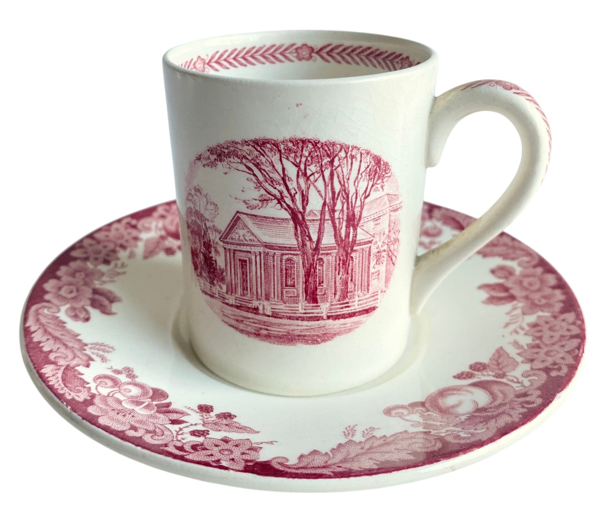 White mug and saucer set with pink floral and house design on a white background