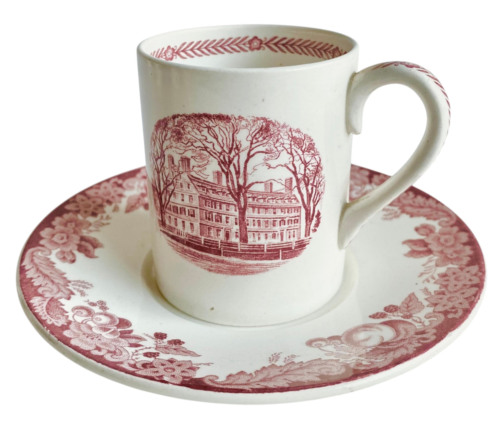 White mug and saucer set with red floral and architectural design on a white background