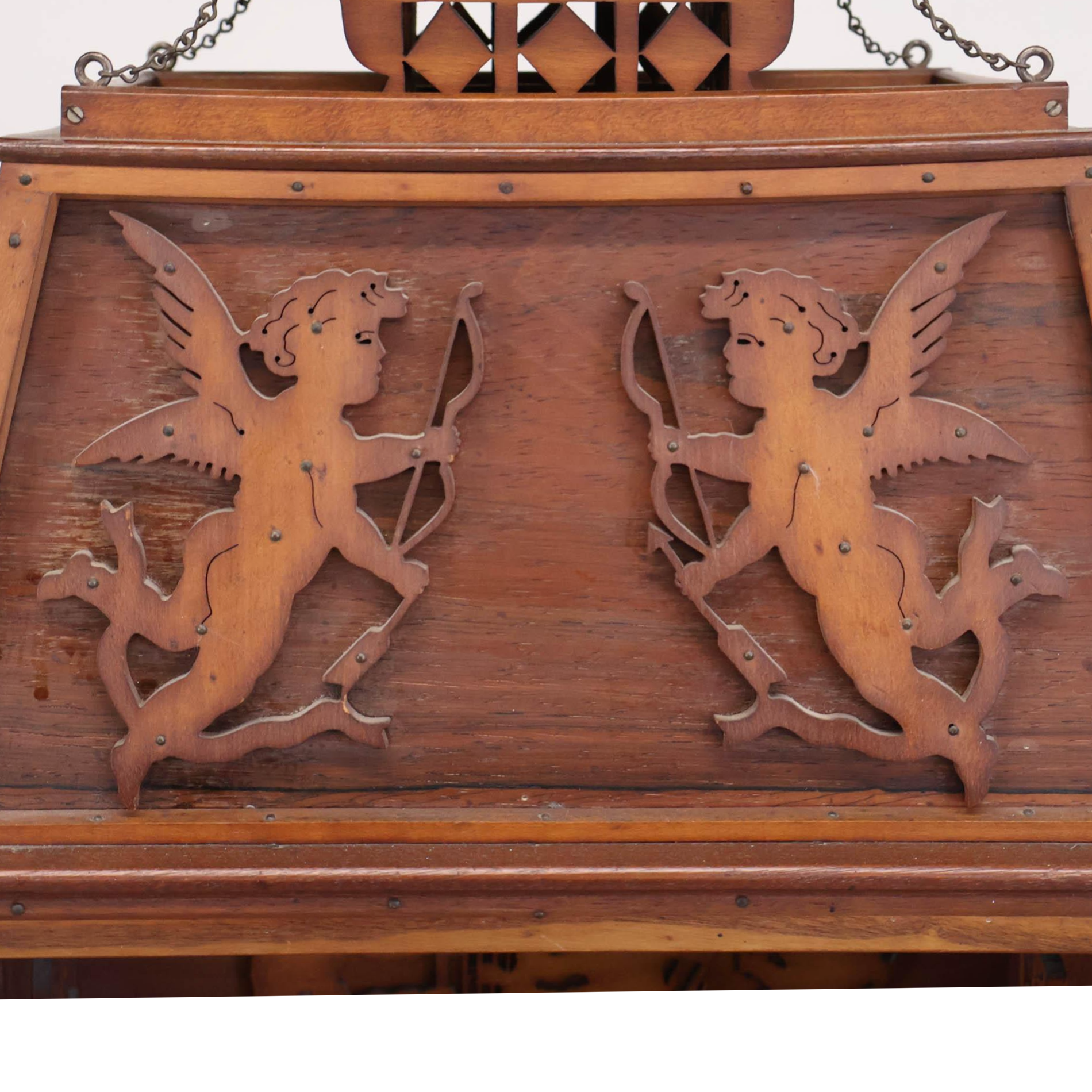Wooden decorative panel with carvings of two cherubs holding bows and arrows.